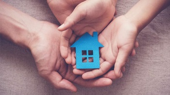 duas mãos seguram uma casa para habitação acessível